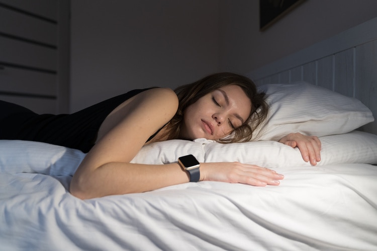 Woman sleeping in bed while wearing apple watch