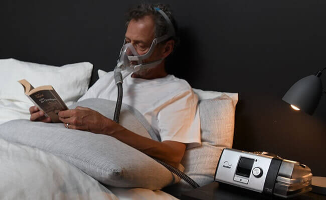 man_copd_lumis_reading_book_bed_full_face_mask