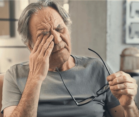  Older man rubbing his eye, looking tired