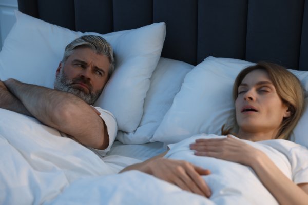  Irritated man lying near his snoring wife in bed