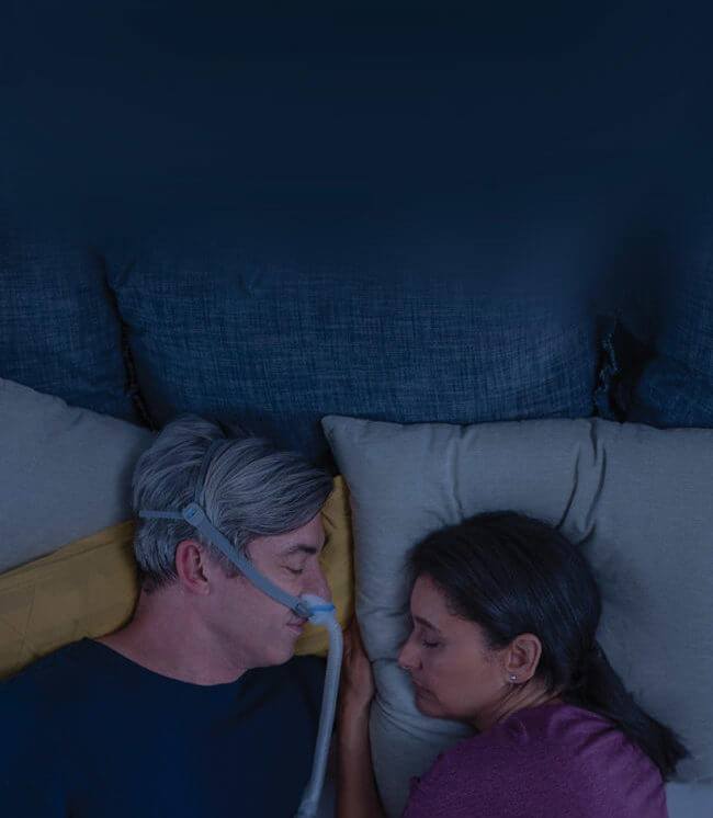 Man sleeping with AirFit N30 CPAP mask close to his wife-mobile image-ResMed Middle East